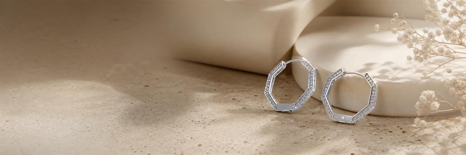 Geometric silver earrings on warm sculptural stone